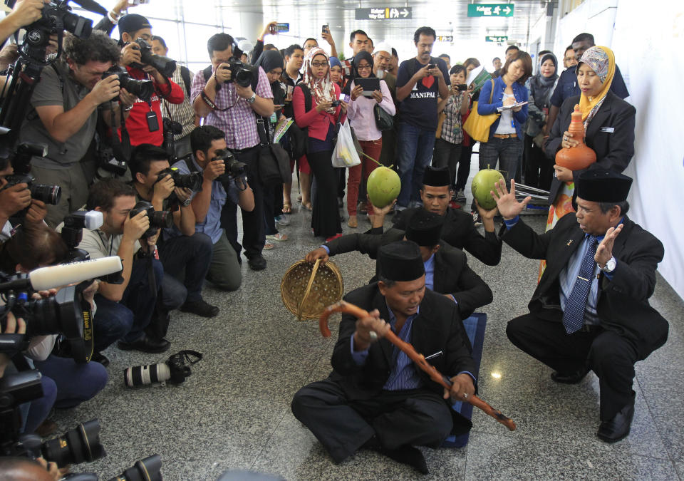 FILE - In this March 12, 2014 file photo, well-known Malaysian shaman Ibrahim Mat Zin, bottom right, uses spiritual methods and prayers to locate the missing Malaysia Airlines plane MH370 at Kuala Lumpur International Airport in Sepang, Malaysia. Solving the mystery of the missing Malaysian plane is proving to be as easy as cracking a homicide without a body, witness or motive. All while billions of people are waiting for the kind of quick and clear resolution that we’ve come to expect in the information age _ and speculating in sometimes wild ways when that resolution doesn’t come. (AP Photo/Lai Seng Sin, File)