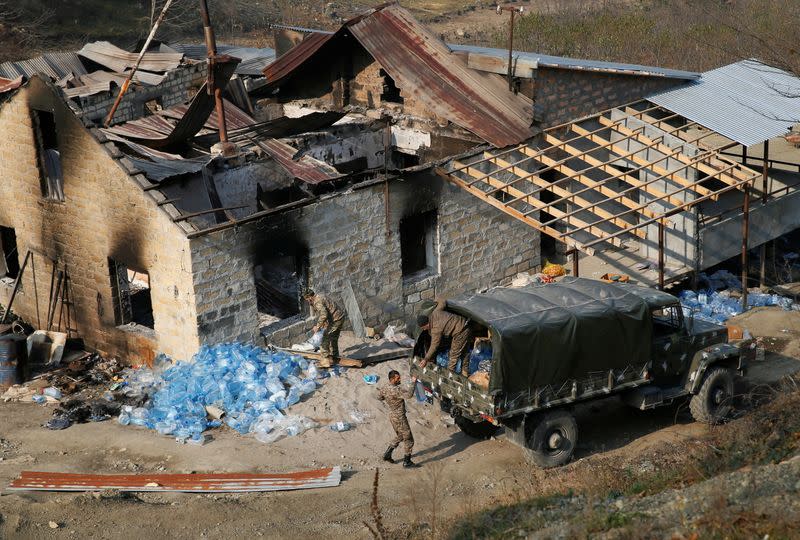 Ethnic Armenian soldiers load bottles with water into the truck in the village of Knaravan