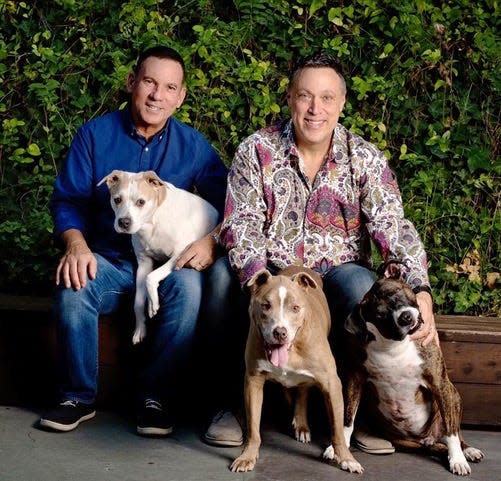 Michael Levitt, right, poses with his husband, Marc, and their three rescue dogs.