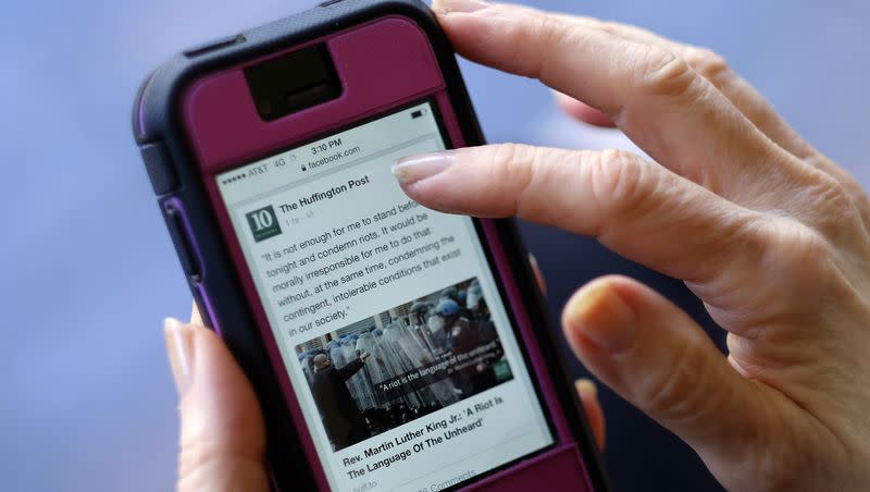 In this April 28, 2015, file photo, an Associated Press staffer poses using a mobile phone to read the news from HuffPost on Facebook, in Los Angeles.