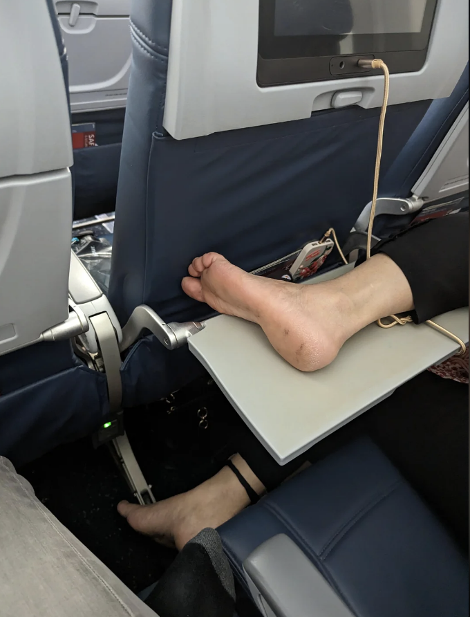 a person's feet on someone's tray table in a plane