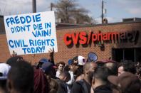 Demonstrators hold up a placard near the CVS Pharmacy that was looted and burned on Pennsylvania Avenue in Baltimore, Maryland, April 28, 2015