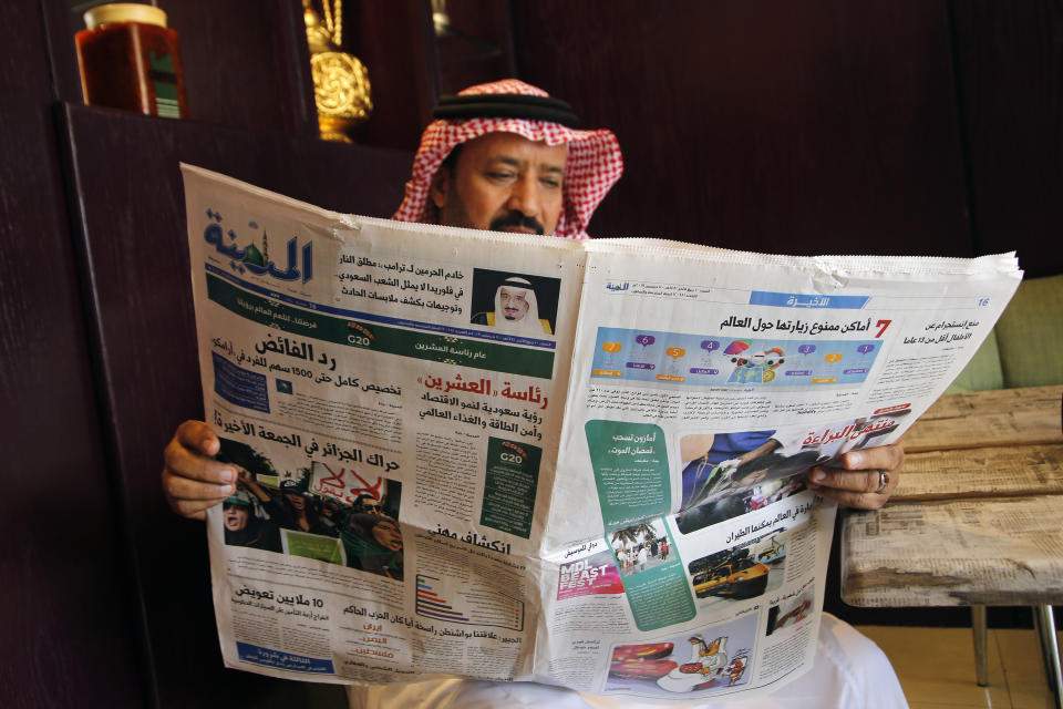 A man reads the daily Al-Madina newspaper fronted by a picture of Saudi King Salman at a coffee shop in Jiddah, Saudi Arabia, Saturday, Dec. 7, 2019. U.S. law enforcement officials were digging into the background of the suspected Florida naval station shooter Friday, to determine the Saudi Air Force officer's motive and whether it was connected to terrorism. Arabic at top reads "King Salman to Donald J. Trump: the Florida shooter does not represent the Saudi people." (AP Photo/Amr Nabil)
