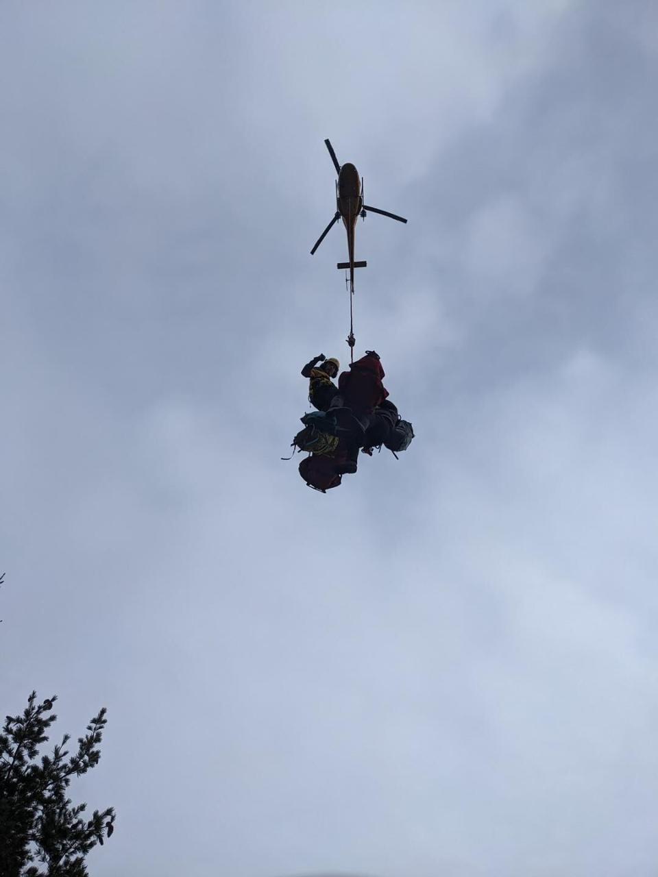 A Talon helicopter hauls a North Shore Rescue technician and the climber injured on the East Lion.