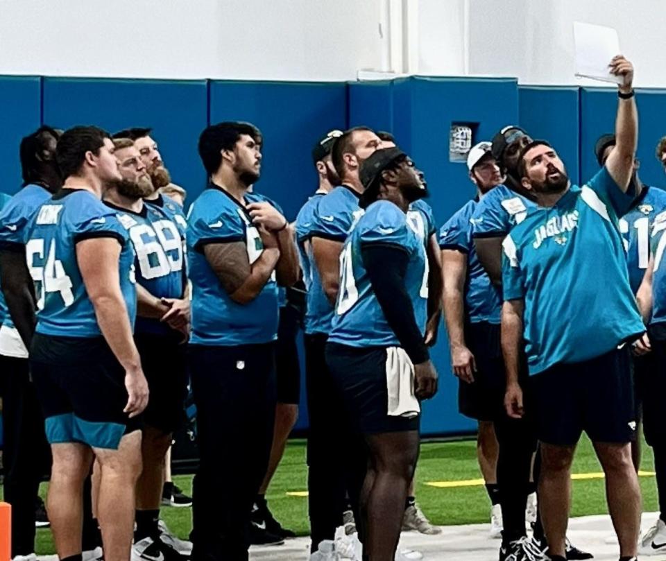 Jaguars offensive line coach Phil Rauscher shows players details of a formation during Monday's training camp practice at the Miller Electric Indoor Center.