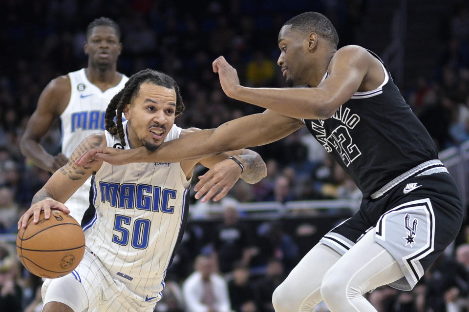 Orlando Magic guard Cole Anthony (50) is fouled by San Antonio Spurs guard Malaki Branham (22) while driving to the basket during the first half of an NBA basketball game Friday, Dec. 23, 2022, in Orlando, Fla. (AP Photo/Phelan M. Ebenhack)