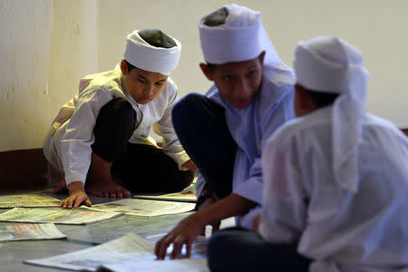 Madrasa students read a newspaper at Muhammadi Mosque before Friday prayers in Kota Bharu, Malaysia April 13, 2018. REUTERS/Stringer