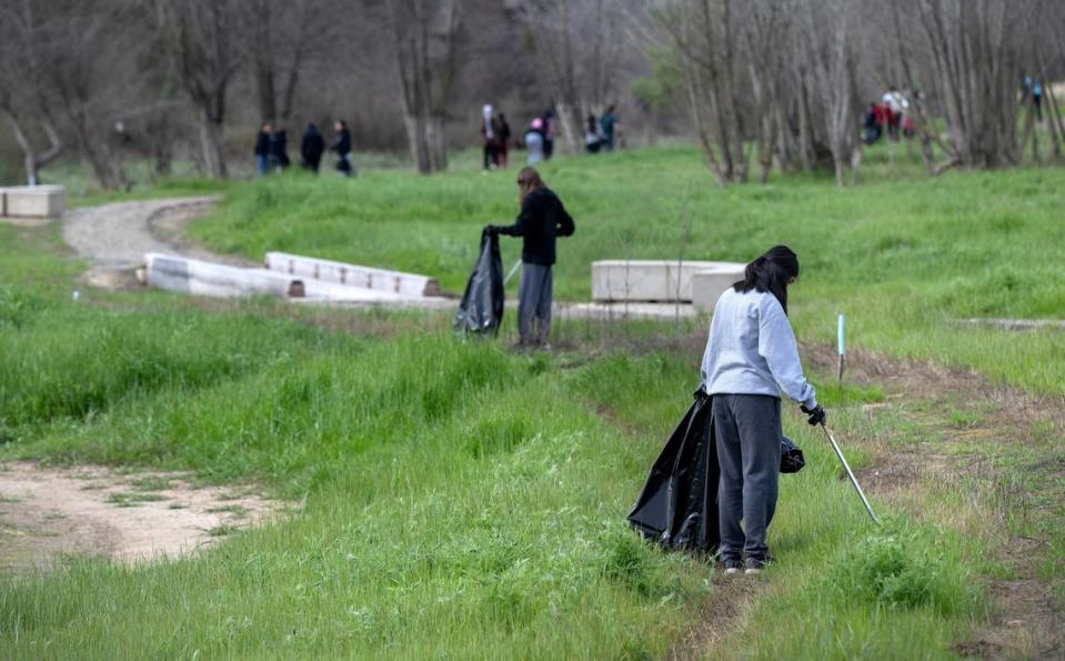 Volunteer Jennylyn Patague picks up trash as part of the Operation 9-2-99 river cleanup along the Tuolumne River in Modesto, Calif., Saturday, March 9, 2024.