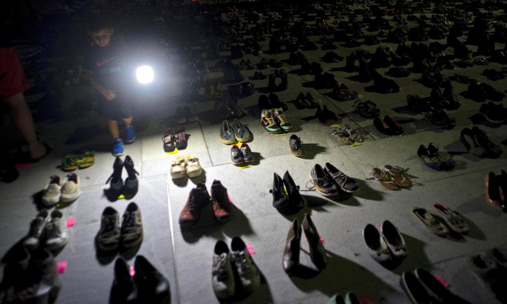 A child shines a light on hundreds of shoes at a memorial for those killed by Hurricane Maria, in front of the capitol in San Juan.