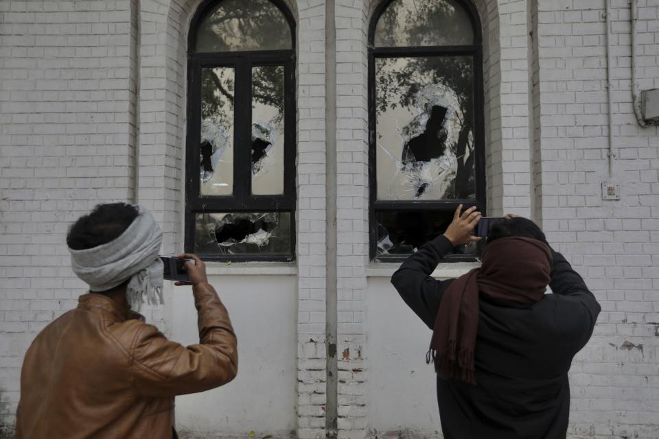 Students take photographs broken windows of the Jamia Millia Islamia University library that was stormed by police Sunday in New Delhi, India, Monday, Dec.16, 2019. Police on Sunday fired tear-gas and struck with batons students who protested against a new law that will give citizenship to non-Muslims fleeing religious persecution from several neighboring countries. (AP Photo/Manish Swarup)