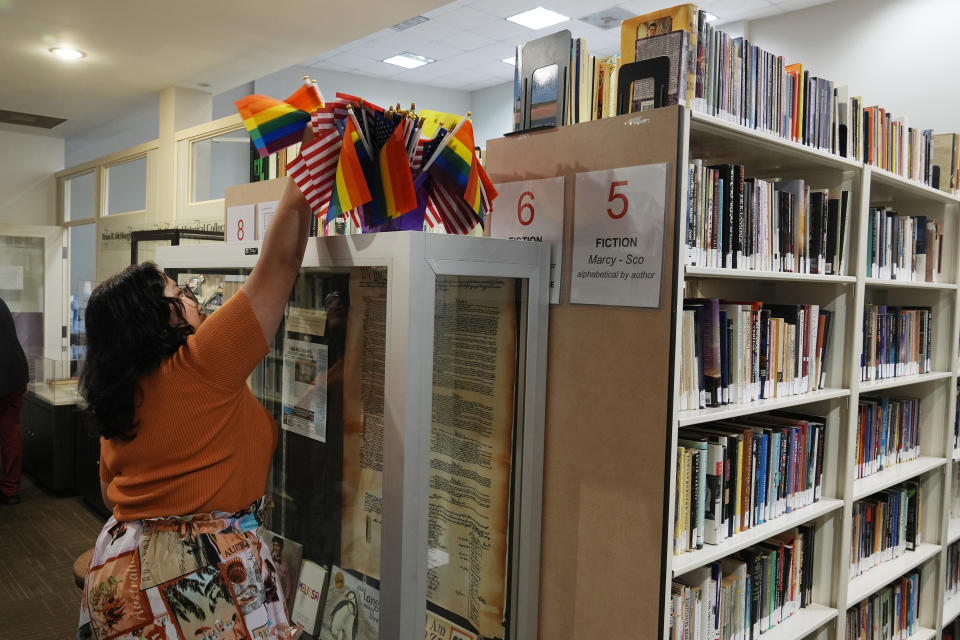 A summer intern places a rainbow flags in the Stonewall Museum library, Wednesday, June 26, 2024, in Fort Lauderdale, Fla. The Stonewall Museum hosts a comprehensive archive on LGBTQ+ history and the largest library collection in the world. The museum is one of hundreds of art and culture groups in the state that are left scrambling to plug a large budget gap after Gov. Ron De Santis vetoed $32 million in arts funding. (AP Photo/Marta Lavandier)