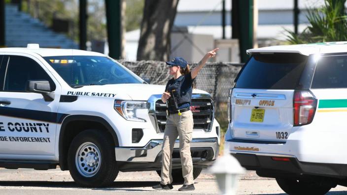 A code enforcement officer directs parents to the parking lot to pick up their children at the Manatee County Fairgrounds in Palmetto after a bomb threat forced a full evacuation of Parrish Community High School Tuesday morning.