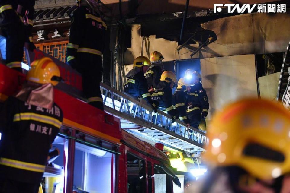 火勢雖已撲滅，現場消防人員仍繼續緊急搶救傷者。（圖／新華社）