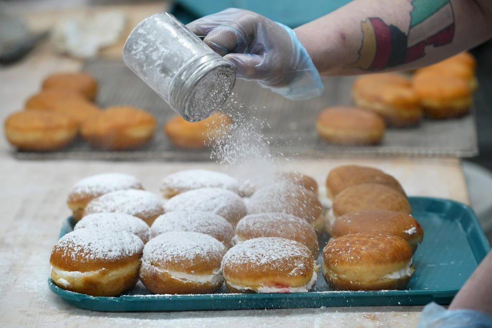 Bismark donuts are showered with powdered sugar at Leavitt's Country Bakery, Thursday, April 13, 2023, in Conway, N.H. (AP Photo/Robert F. Bukaty)