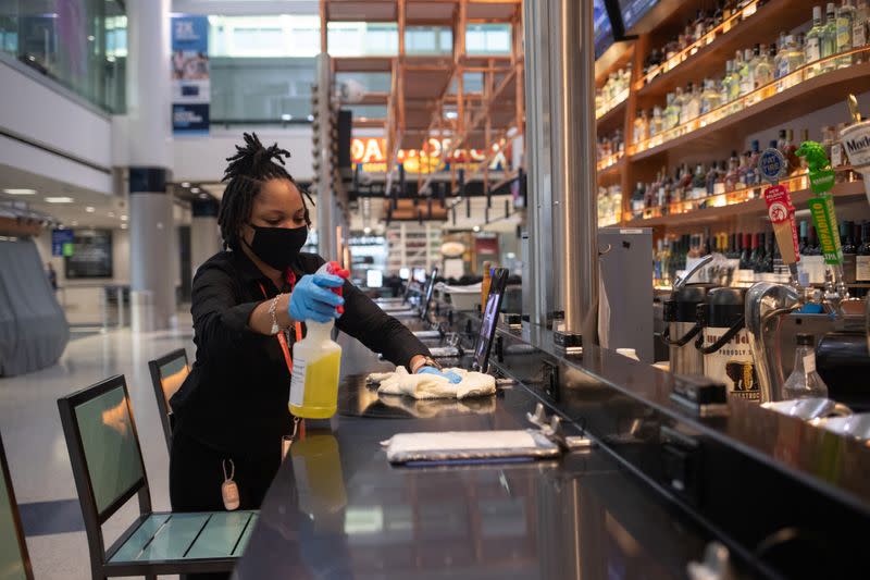 A woman cleans and disinfects a bar at IAH George Bush Intercontinental Airport in Houston