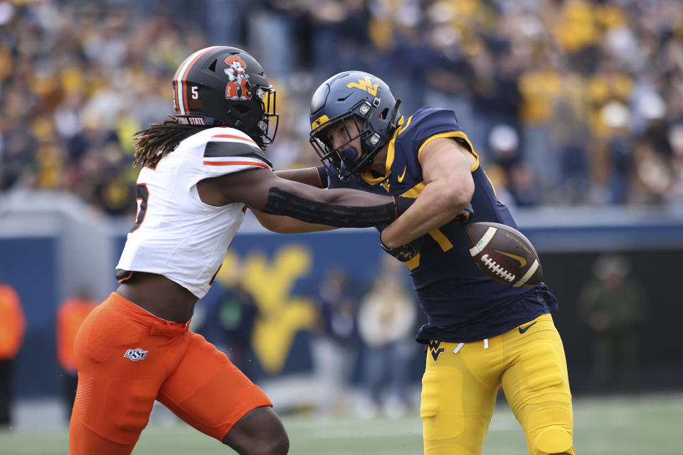 Oklahoma State's Kendal Daniels, left, forces a fumble by West Virginia's Kole Taylor, right, after a catch during the first half of an NCAA college football game Saturday, Oct. 21, 2023, in Morgantown, W.Va. (AP Photo/Chris Jackson)