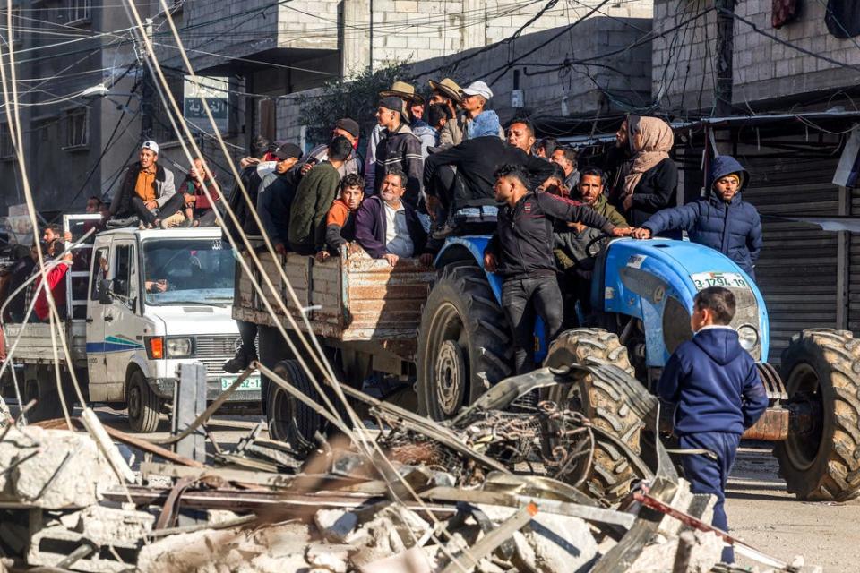 People ride in a cart pulled by a tractor past the rubble of a destroyed building and a mosque minaret in Rafah in the southern Gaza Strip on Feb. 14, 2024.