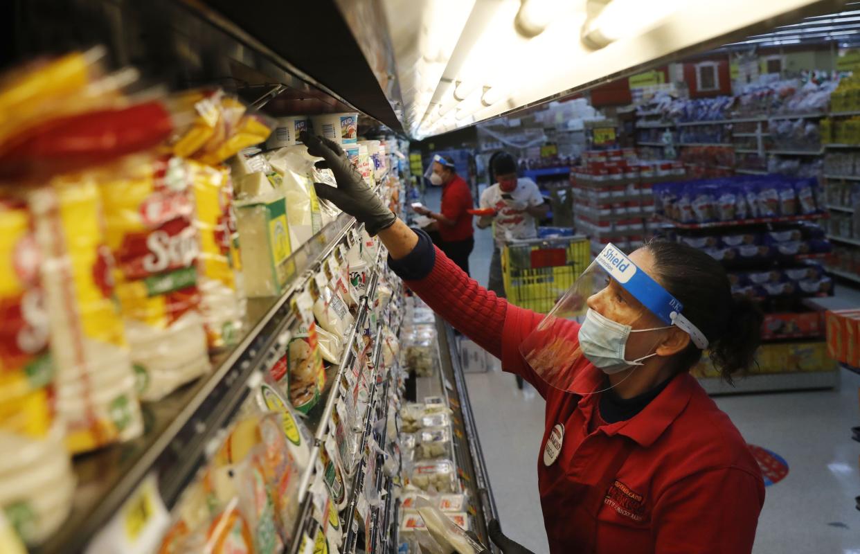 Maclola Orozco wears protective gear as a precaution against the coronavirus as she restocks shelves at El Rancho grocery store in Dallas, Texas on Monday, April 13, 2020.