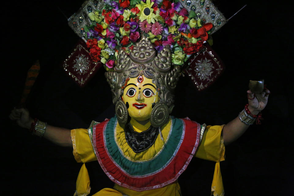 In this Sept. 23, 2018, photo, a dancer poses for photographs wearing goddess Mahalaxmi mask in Kathmandu, Nepal. For centuries, Nepal has celebrated the Indra Jatra festival of masked dancers, which officially begins the month-long festivities in the Hindu-dominated Himalyan nation. The dancers, who come from a variety of backgrounds, pull off this performance every year despite minimal financial support from the government and other sources, they say. (AP Photo/Niranjan Shrestha)