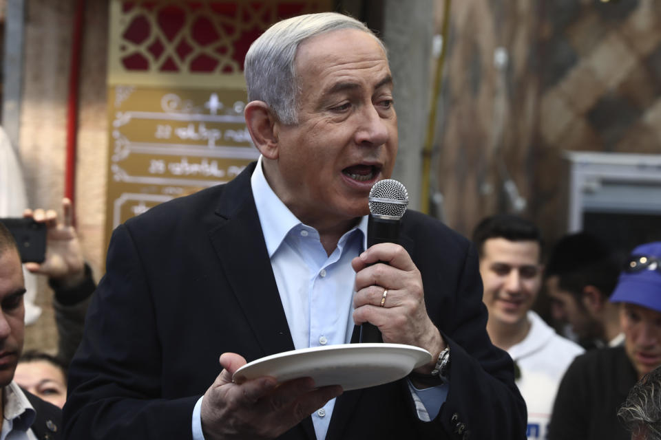 Israeli Prime Minister and head of the Likud party Benjamin Netanyahu holds a plate as he speaks during a visit to a market in Jerusalem, Friday, Feb. 28, 2020. (AP Photo/Oded Balilty)
