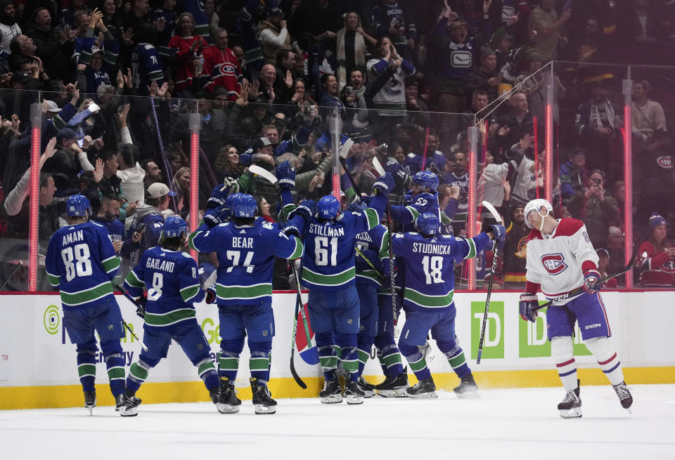 Vancouver Canucks players celebrate Elias Pettersson's winning goal against the Montreal Canadiens during overtime of an NHL hockey game in Vancouver, British Columbia, Monday, Dec. 5, 2022. (Darryl Dyck/The Canadian Press via AP)