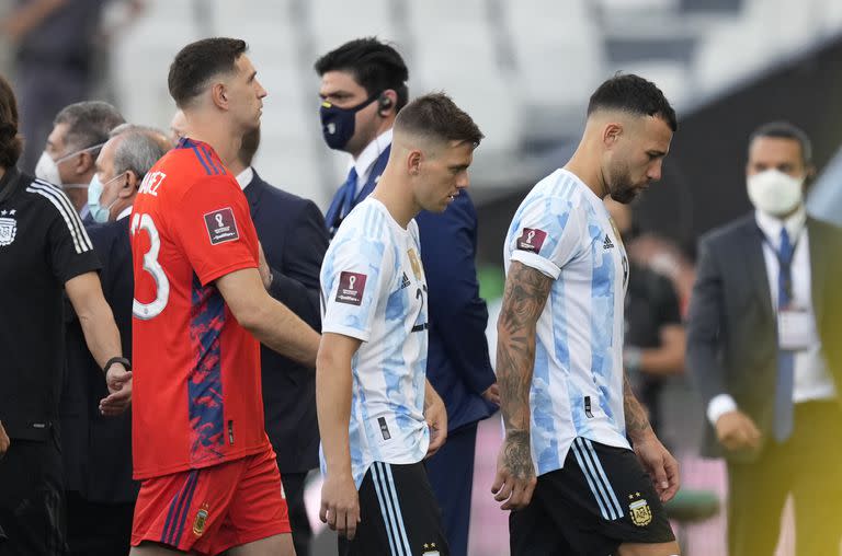 Desde la derecha, los jugadores argentinos Nicolás Otamendi, Giovani Lo Celso y Emiliano Martínez se retiran de la cancha tras la interrupción del partido contra Brasil por las eliminatorias del Mundial