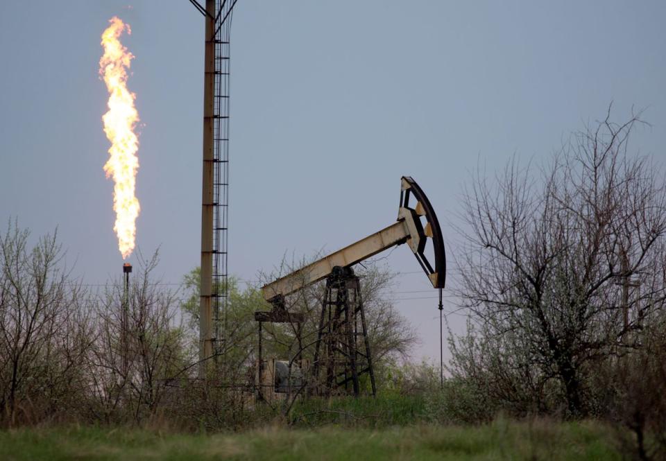 An oil pumping jack, also known as a 'nodding donkey,' operates beside a flame stack in an oil field near Samara, Russia, on Tuesday, May 14, 2019. The nearby village of Nikolayevka in central Russia has emerged as the epicenter of an international oil scandal with authorities saying corrosive chlorides entered Russias 40,000-mile network of oil pipelines, causing the first-ever shutdown of the main export artery to Europe. (Andrey Rudakov/Bloomberg via Getty Images)