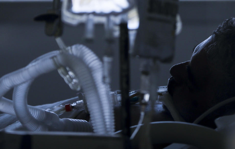 A COVID-19 patient lies in the intensive care unit of a hospital in Buenos Aires, Argentina, Tuesday, Aug. 18, 2020. At a time when the number of deaths due to COVID-19 has increased in Argentina, several hospitals are implementing protocols on their own initiative that allow people to say goodbye to their loved ones in person, differing from the usual practice whereby the family loses all contact with the patient in hospital and he or she dies in isolation from their family. (AP Photo/Natacha Pisarenko)