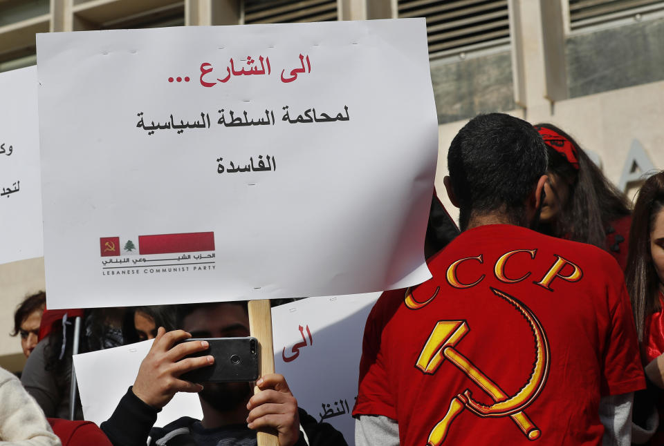 A demonstrator holds a placard that reads: "Off to the Streets, to bring to trial the corrupt political authority," during an anti-government protest organized by the country's communist party, in Beirut, Lebanon, Sunday, Dec. 16, 2018. Hundreds of Lebanese called for an end to a stalemate over forming a government seven months after elections. The Sunday protests were organized by the country's vibrant communist party, but drew others frustrated by the country's deepening economic and political crisis. (AP Photo/Hussein Malla)