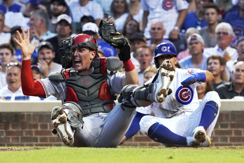 Cincinnati Reds catcher Tyler Stephenson holds up the glove and ball after tagging out Chicago Cubs' Rafael Ortega, right, during the third inning of a baseball game Tuesday, July 27, 2021, in Chicago. (AP Photo/David Banks)