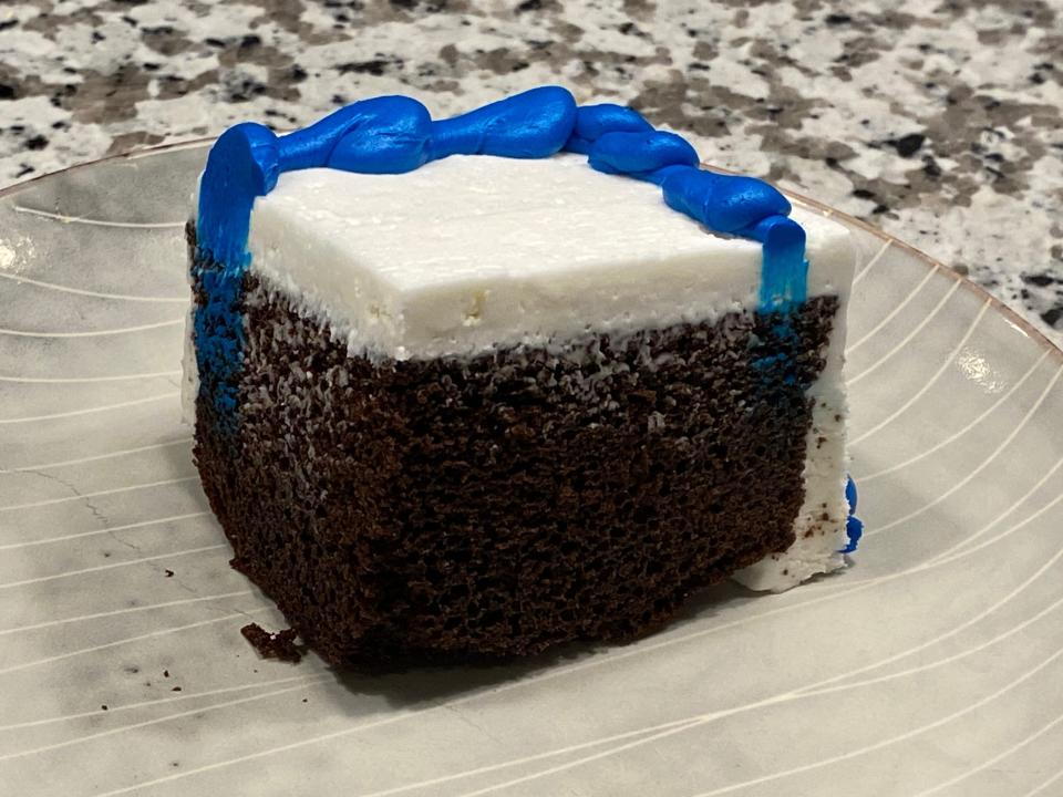 corner slice of chocolate cake with white frosting and blue border on top