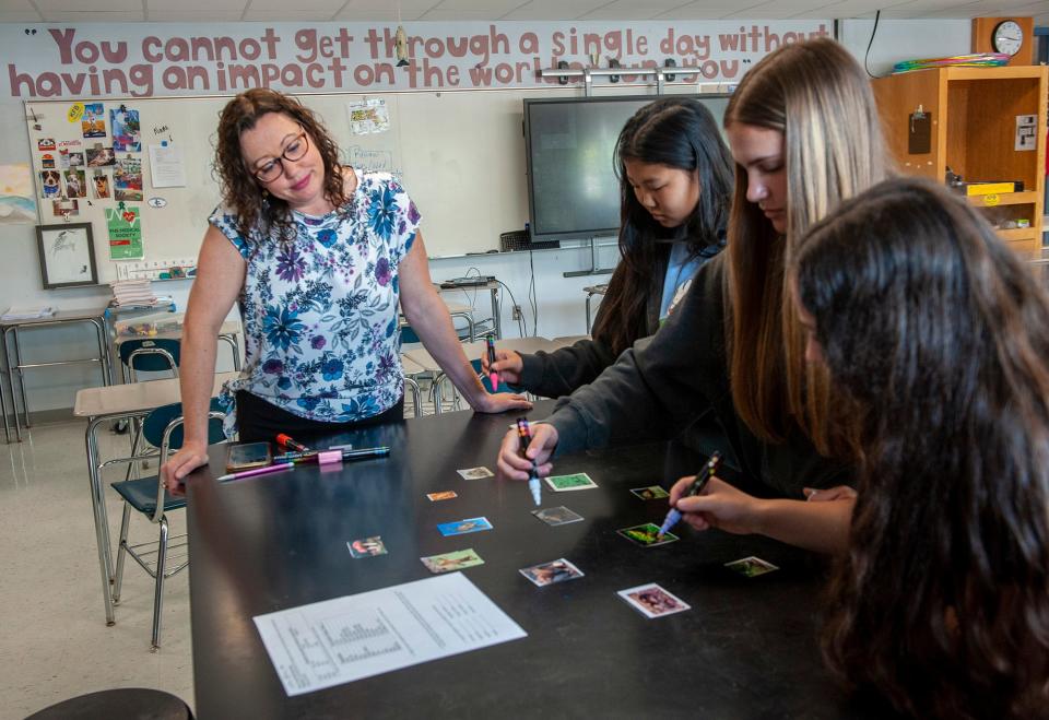 Framingham High School teacher Rebecca Maynard, left, works with ninth grade honors biology students Aubrey Park, Cydney Ebel and Nora Herbert on a food web showing the trophic relationships of organisms in the ecosystem, May 14, 2024.