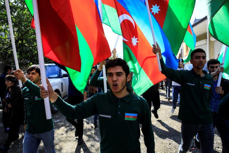 People hold Azerbaijan's national flags and shout slogans during the funeral of Anar Aliyev and his wife Nurcin Aliyeva in the city of Shamkir