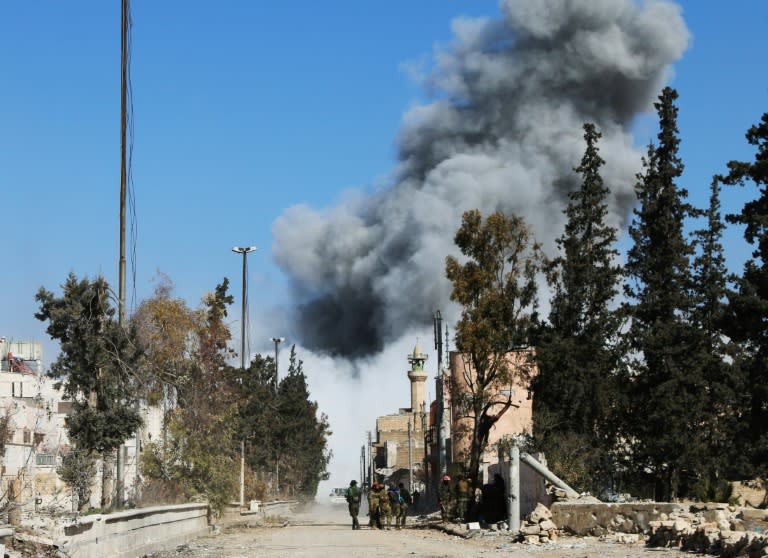 Opposition fighters backing Turkish troops gather on a road as smoke billows following an air strike on an Islamic State (IS) group position on February 21, 2017, in the Syrian town of al-Bab