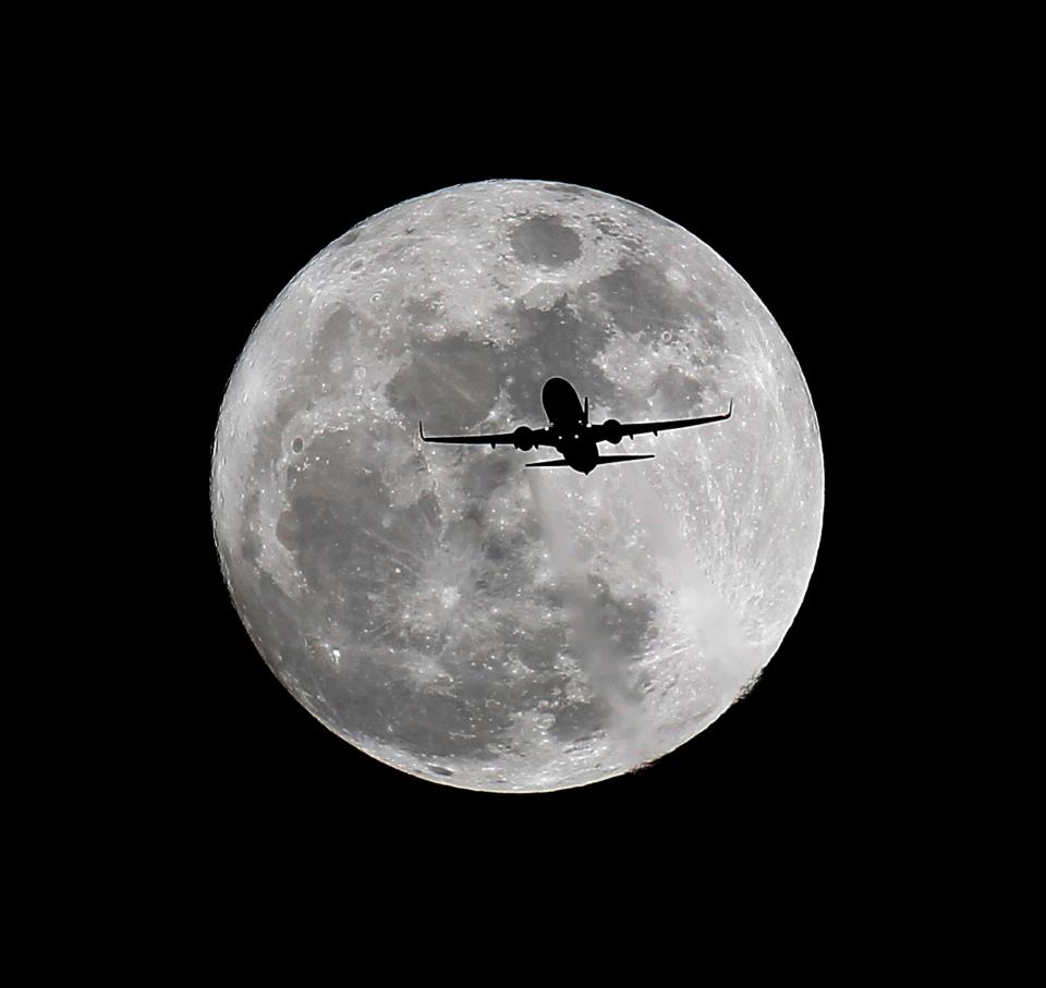 A commercial airliner crosses the first full moon of the year, called the wolf moon, over Whittier, Calif., on its way to Los Angeles in 2015.