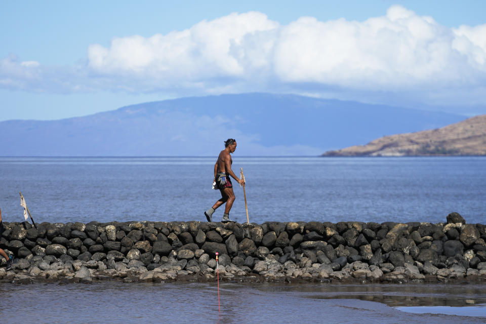 CORRECTS LAST NAME TO RUBIO, NOT RUBOI - Vicente Rubio walks along a sea wall, Tuesday, Aug. 15, 2023, in Kihei, Hawaii, following wildfires that ravaged Maui. (AP Photo/Rick Bowmer)