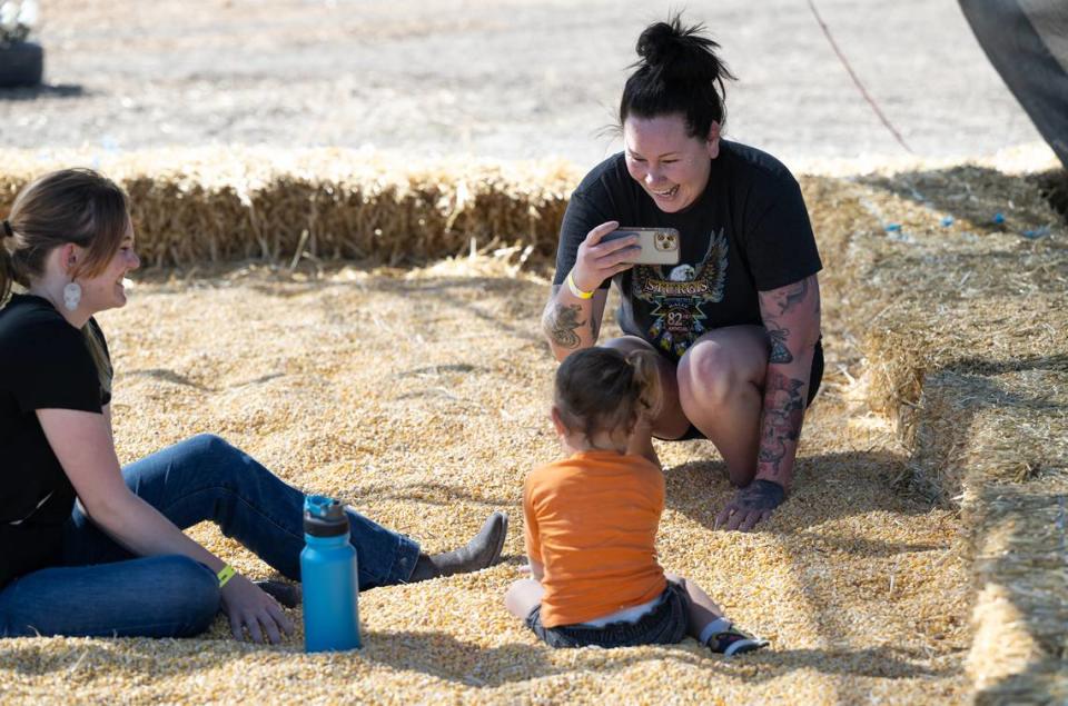 Bee reporter Dominique Williams, right, and her niece Josie, 2, play in the corn pit with Kensey Cope, left, at Dutch Hollow Farms in Modesto, Calif., Thursday, Oct. 5, 2023.