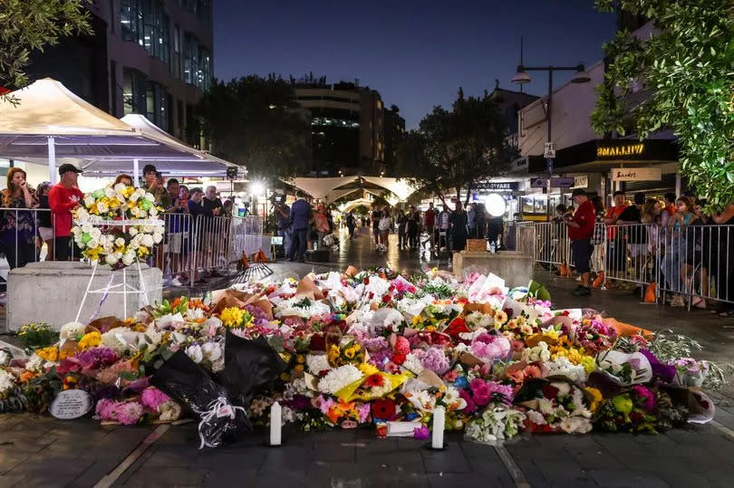 Members of the public look at flowers placed outside the Westfield Bondi Junction shopping mall in Sydney