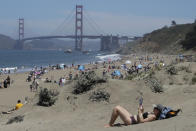 Sara Stewart, foreground, reads a book while away from crowds visiting Baker Beach during the coronavirus outbreak in San Francisco, Sunday, May 24, 2020. (AP Photo/Jeff Chiu)