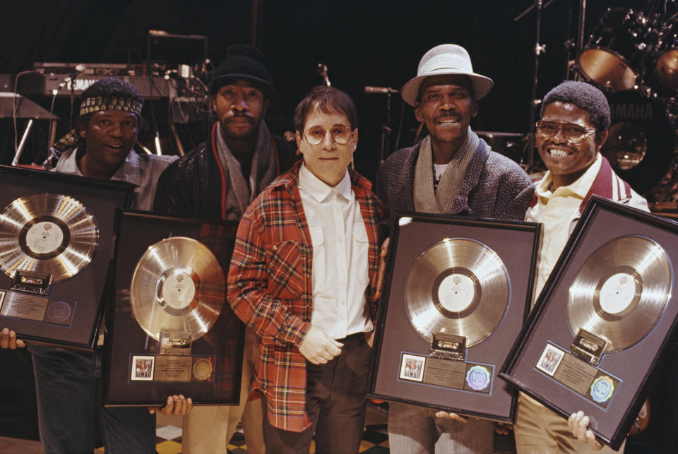 American singer-songwriter Paul Simon of folk rock duo Simon & Garfunkel posed with four musicians, all holding gold discs of Paul Simon's album Graceland, on which they contributed, London, 1987.