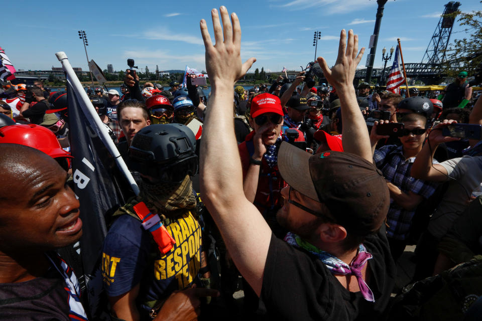 <p>A counterprotester raises his arms as he talks with supporters of the Patriot Prayer group during a rally in Portland, Ore., Aug. 4, 2018. (Photo: Bob Strong/Reuters) </p>