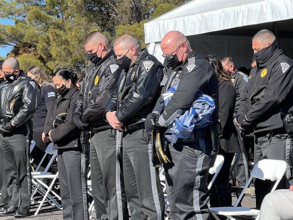 New Mexico State Police officers stand with heads bowed outside the NMSP station in Deming during a ceremony commemorating the anniversary of NMSP officer Darian Jarrott's death, Friday, Feb. 4, 2022.