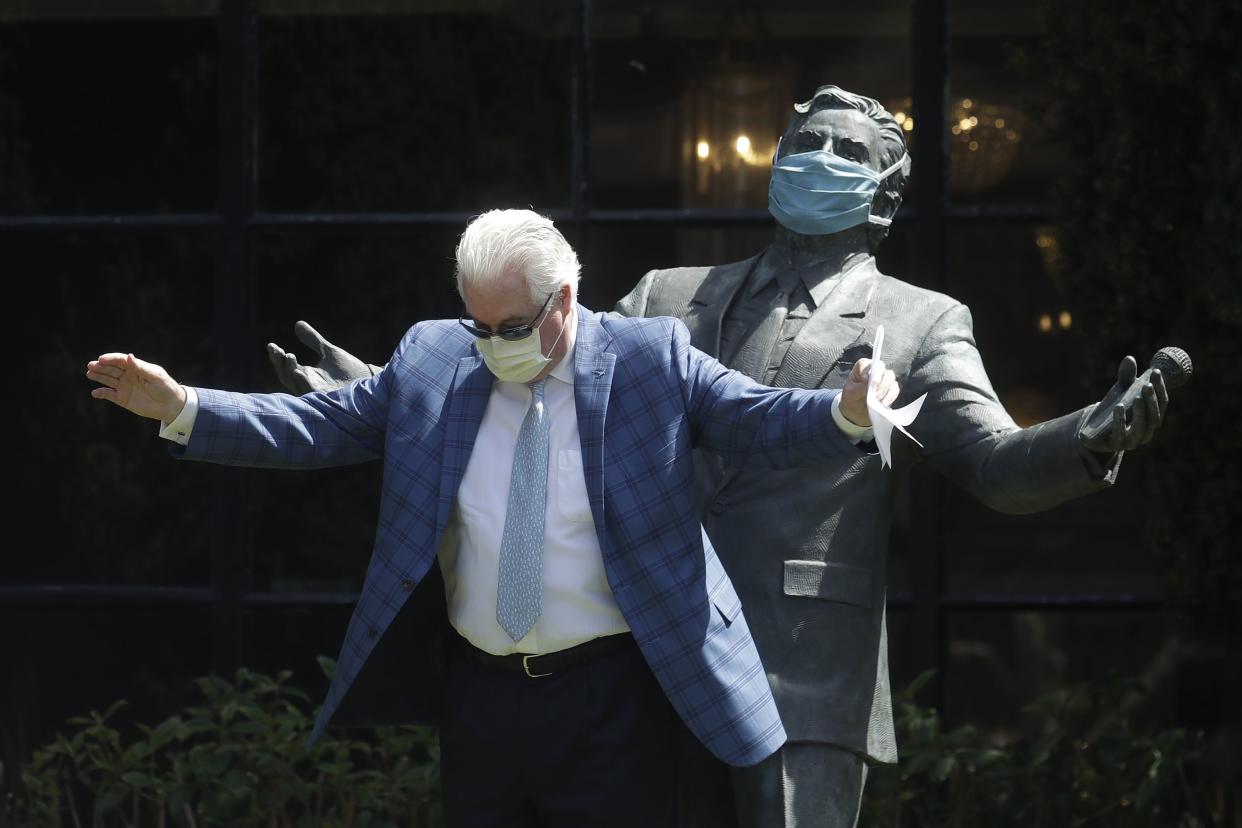 Paul Tormey, Regional Vice President of Fairmont Hotels, wears a mask while gesturing in front of a statue of singer Tony Bennett outside of the Fairmont San Francisco hotel after leading hotel workers in a singing of the song "I Left My Heart in San Francisco" on Saturday, April 25, 2020, in San Francisco, Calif. Bennett had encouraged San Franciscans to join him in a sing-a-long from their homes during shelter in place orders for COVID-19 concerns.