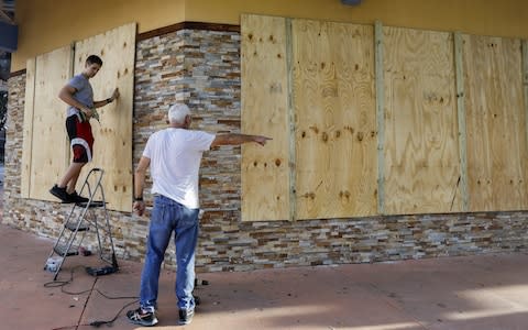 A business owner boards up windows of a restaurant in downtown Florida  - Credit: ERIK S. LESSER/EPA