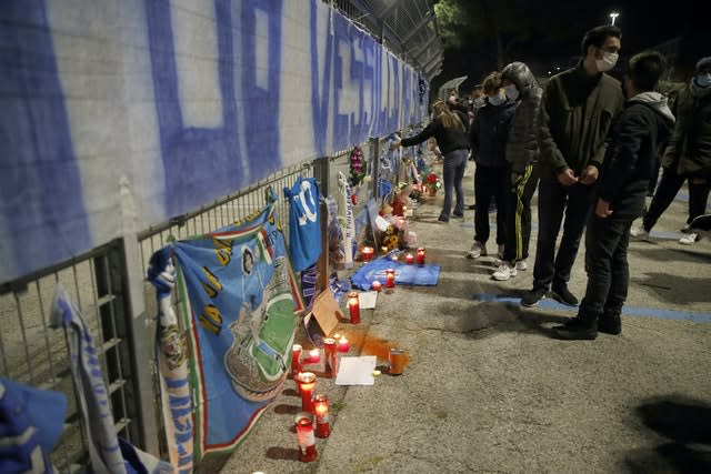 People lay flowers and light candles as they gather outside the San Paolo Stadium 