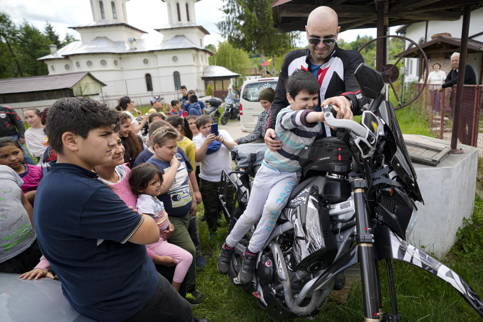 Children pose on motorcycles belonging to the members of the group Bikers for Humanity during an eyesight examination event, in Nucsoara, Romania, Saturday, May 29, 2021. (AP Photo/Vadim Ghirda)