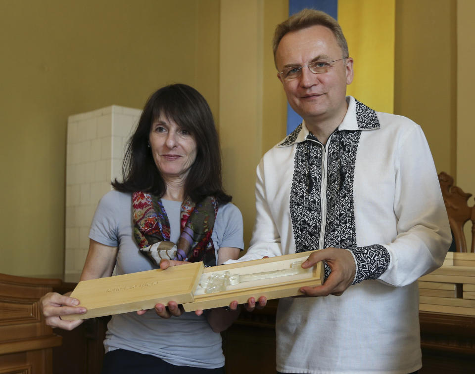 Lviv Mayor Andriy Sadoviy, right, presents a glass copy of an old metal synagogue key to Marla Raucher Osborn, a Jewish heritage project leader, at a ceremony commemorating the 75th anniversary of the annihilation of the city's Jewish population by Nazi Germany in Lviv, Ukraine, Sunday, Sept. 2, 2018. The commemoration comes amid a larger attempt in Ukraine to remember and celebrate the lost Jewish world in a part of Ukraine that before World War II was part of Poland and was the third largest Polish Jewish community. (AP Photo/Yevheniy Kravs)