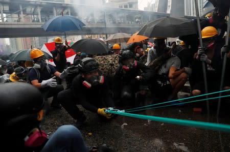 Anti-extradition bill protesters use a slingshot to hurl bricks as they clash with riot police during a protest to demand democracy and political reforms, at Tsuen Wan, in Hong Kong
