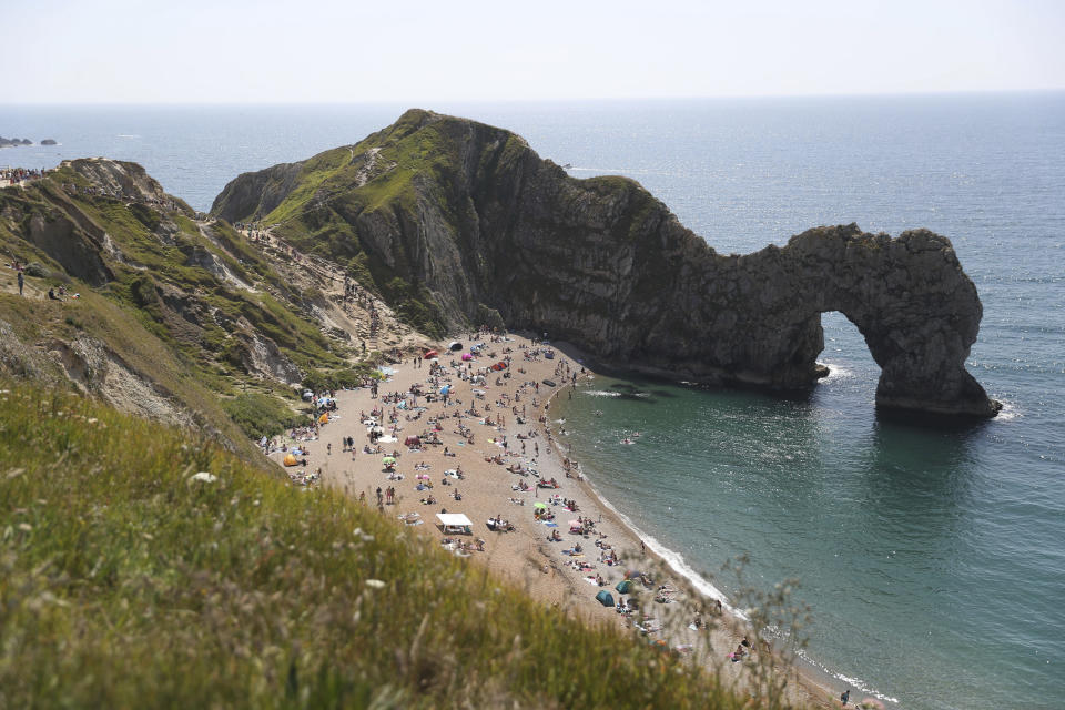 People relax on the beach of Durdle Door beach, as the public are being reminded to practice social distancing following the relaxation of coronavirus lockdown restrictions, near Lulworth in Dorset, England, Saturday May 30, 2020. (Andrew Matthews/PA via AP)