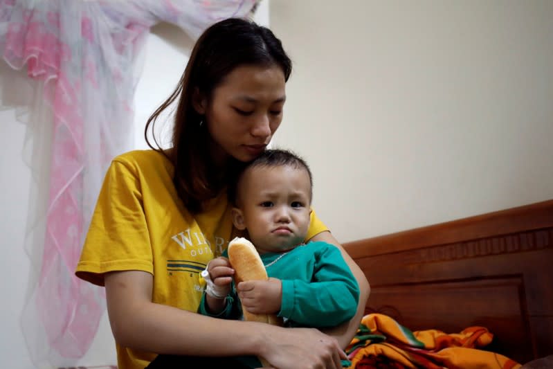 Hoang Thi Thuong, wife of Nguyen Dinh Tu, a Vietnamese suspected victim in a truck container in UK, holds her son Nguyen Dinh Dan at their home in Nghe An province